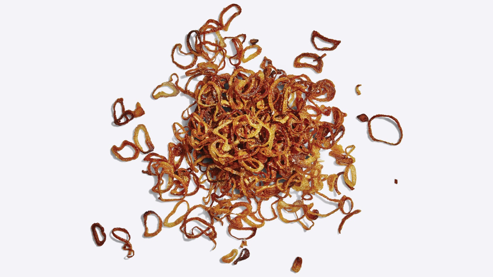A pile of homemade fried shallots on a white surface.